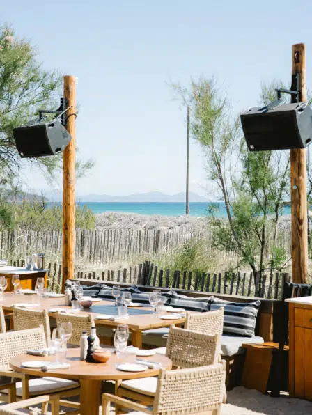 Terrasse restaurant plage Pampelonne face &agrave; la mer, tables dress&eacute;es sur le sable et vue sur les &icirc;les